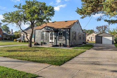 Bungalow featuring a detached garage, an outdoor structure, roof with shingles, driveway, and a front yard