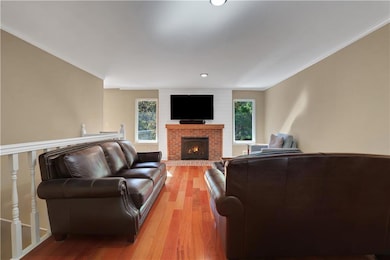 Living room with wood finished floors, crown molding, a fireplace, and recessed lighting
