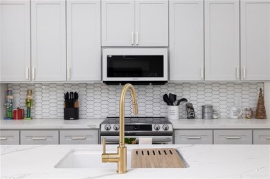 Kitchen with white cabinets, backsplash, and light stone counters