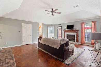 Living area with a ceiling fan, finished concrete flooring, a textured ceiling, baseboards, and a chandelier