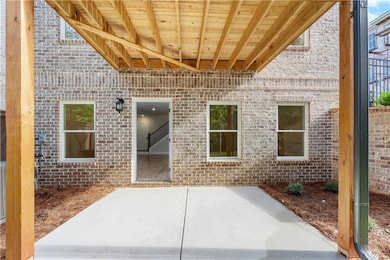 View of exterior entry featuring brick siding and a patio