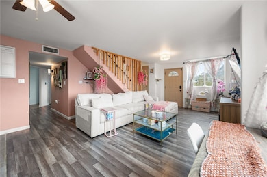 Living area with stairway, wood finished floors, and a ceiling fan
