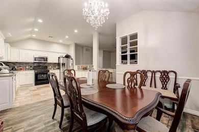 Dining space featuring vaulted ceiling, recessed lighting, light wood finished floors, a chandelier, and ceiling fan