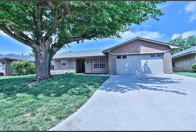 Ranch-style home featuring a garage, brick siding, concrete driveway, and a front yard