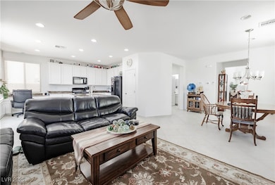 Living area with ceiling fan, a chandelier, recess