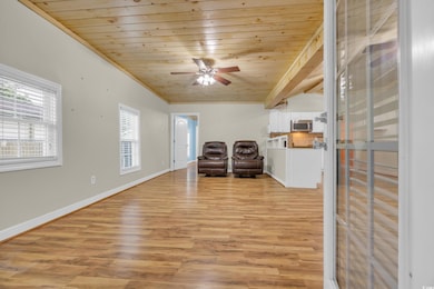 Living room featuring wooden ceiling, plenty of natural light, light wood-style flooring, ceiling fan, and baseboards
