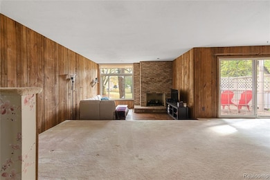 Carpeted living room featuring wood walls and a brick fireplace