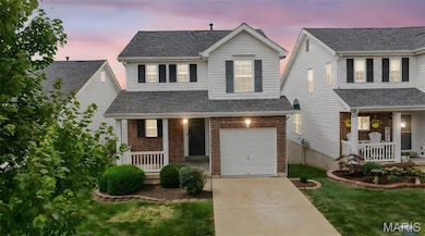 Traditional home with covered porch, driveway, an attached garage, and roof with shingles