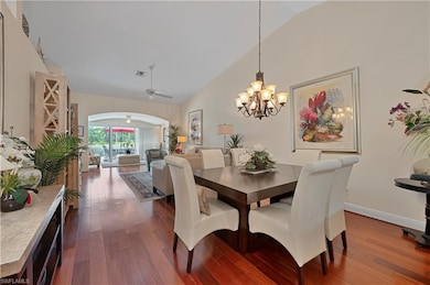 Dining room featuring wood flooring, ceiling fan, chandelier, high vaulted ceiling