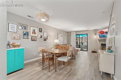 Dining space with wood finished floors and a lit fireplace