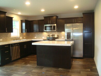 Large kitchen features an island and stainless ste