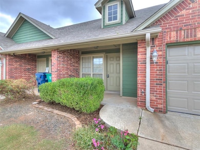 Entrance to property featuring roof with shingles, brick siding, an attached garage, and a porch