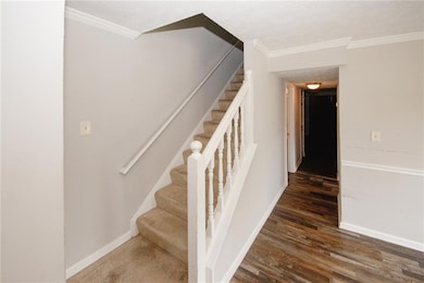 Stairs with wood finished floors, crown molding, and baseboards