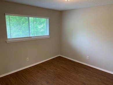 Unfurnished room featuring baseboards and dark woo