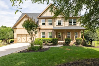 View of front of home featuring brick siding, board and batten siding, concrete driveway, and a front yard