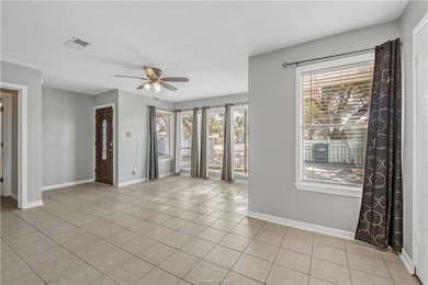 Unfurnished room with ceiling fan and light tile p