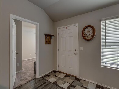 Foyer featuring wood finished floors and vaulted ceiling