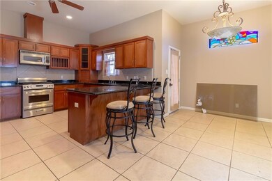 Kitchen featuring stainless steel appliances, ceiling fan, decorative light fixtures, and light tile patterned floors