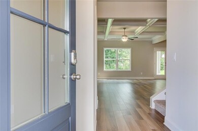 Foyer featuring coffered ceiling, beamed ceiling, wood finished floors, ceiling fan, and stairway