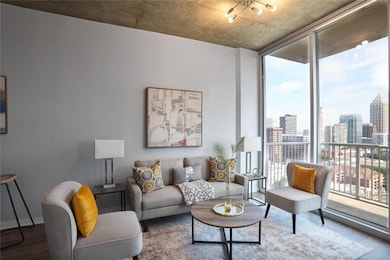 Living area with floor to ceiling windows, a skyline view, and wood finished floors