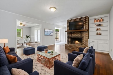 Virtual staging: Living area with wood finished floors, a brick fireplace, ceiling fan, and built in features