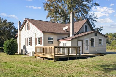 Back of property featuring a lawn, a deck, and cen