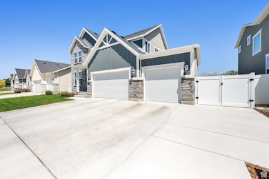 View of front of home featuring a gate, board and batten siding, stone siding, an attached garage, and driveway