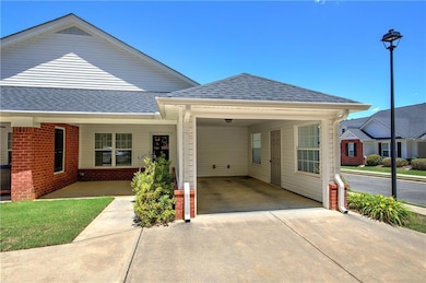 View of front facade featuring driveway, roof with shingles, brick siding, and an attached carport