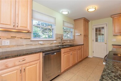 The remodeled Kitchen with black granite counters and natural wood cabinets. The glass pane door leads to the attached garage