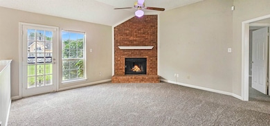 Unfurnished living room with a ceiling fan, lofted ceiling, carpet, a brick fireplace, and a textured ceiling