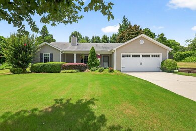 Single story home with a garage, a chimney, driveway, and a front yard