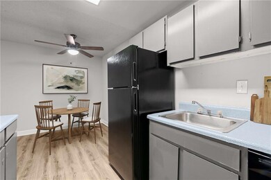 Kitchen featuring a sink, black appliances, light wood-style flooring, ceiling fan, and light countertops