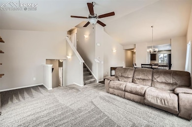 Living area with baseboards, stairway, vaulted cei