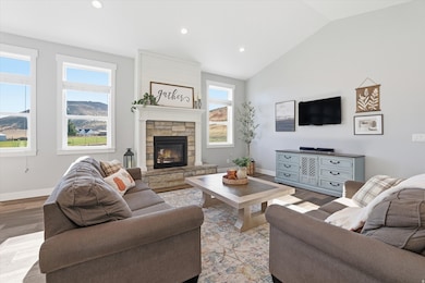 Living area with recessed lighting, wood finished floors, vaulted ceiling, a stone fireplace, and a mountain view