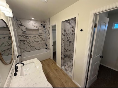 Bathroom featuring wood finished floors, vanity, bathing tub / shower combination, and recessed lighting