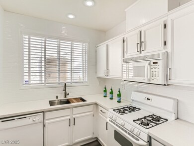 Kitchen featuring white appliances, a sink, light