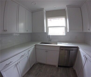 Kitchen with dishwasher, backsplash, white cabine