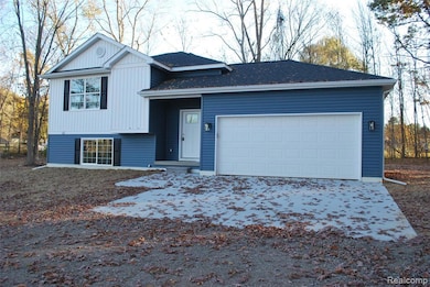 Tri-level home featuring a garage, a shingled roof, and driveway
