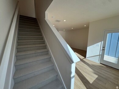Staircase with wood finished floors and recessed lighting