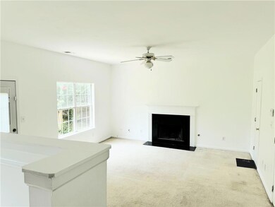 Unfurnished room featuring light colored carpet, ceiling fan, and a fireplace with flush hearth and bright windows