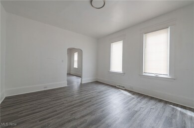 Empty room with arched walkways and dark wood-type flooring