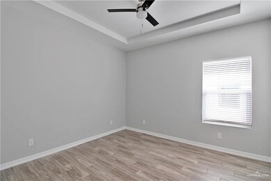 Unfurnished room featuring light wood-type flooring, ceiling fan, and a raised ceiling