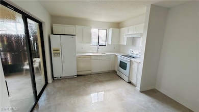 Kitchen featuring white appliances, a textured cei
