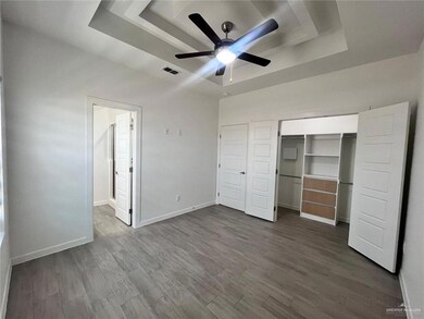 Unfurnished bedroom with a raised ceiling, hardwood / wood-style flooring, ceiling fan, and a closet