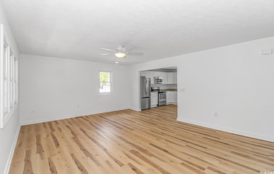 Unfurnished living room featuring ceiling fan, lig