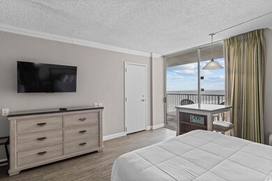 Bedroom featuring a wall of windows, wood finished floors, access to outside, a water view, and a textured ceiling