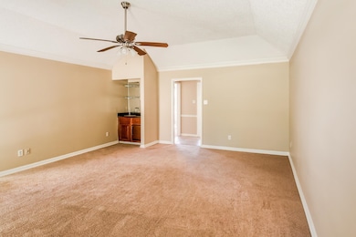 Unfurnished living room with vaulted ceiling, light colored carpet, crown molding, ceiling fan, and a textured ceiling