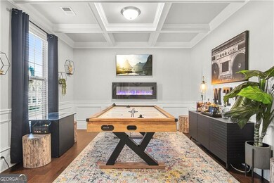 Playroom with dark hardwood / wood-style flooring, beamed ceiling, coffered ceiling, and ornamental molding