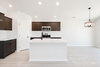 Kitchen with dark brown cabinets, recessed lighting, hanging light fixtures, a kitchen island with sink, and stainless steel appliances
