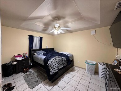 Bedroom featuring a raised ceiling, ceiling fan, and light tile patterned floors